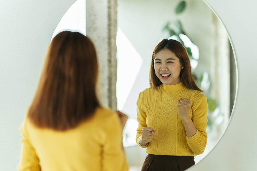 A young woman talks to herself in the mirror