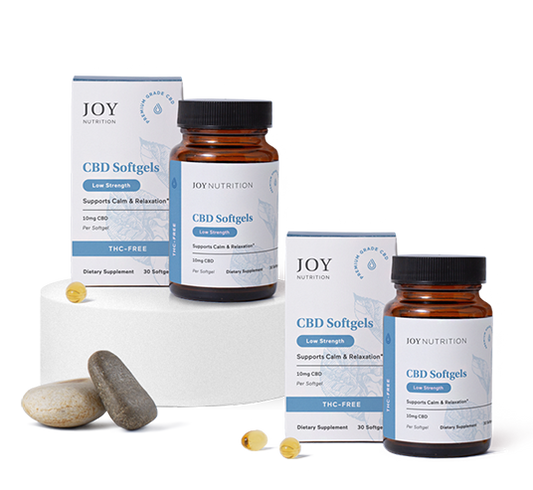 Two amber bottles and boxes of Joy Nutrition CBD Softgels with loose softgel capsules displayed in front.