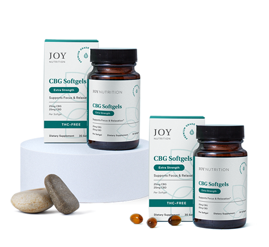 Two boxes and two amber bottles of CBG softgels with loose softgel capsules and stones displayed in front.
