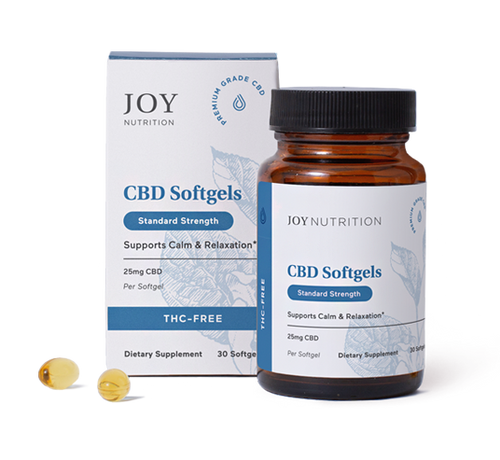 Joy Nutrition CBD softgel capsules in amber glass bottle with white product box and two loose yellow capsules displayed in fr