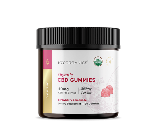 Dark glass jar with black ribbed cap containing strawberry-colored gummies, labeled "Joy Organics Organic CBD Gummies 10mg St